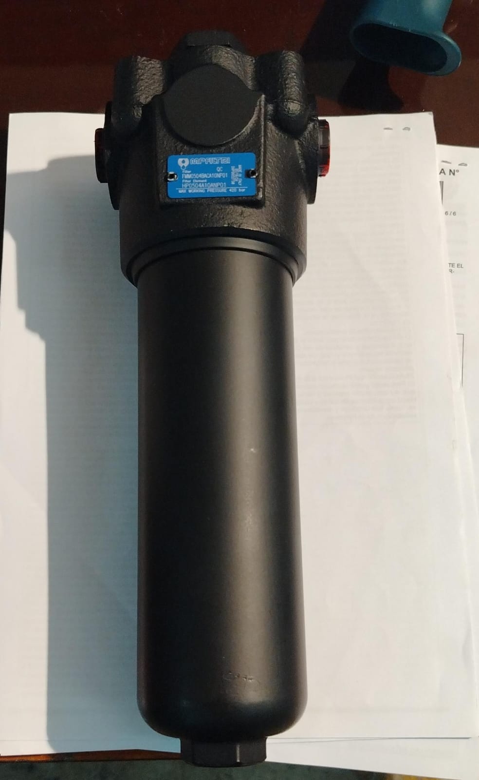 Carcasa de filtro hidráulico MP Filtri con su placa azul de identificación, sobre hojas de documentación