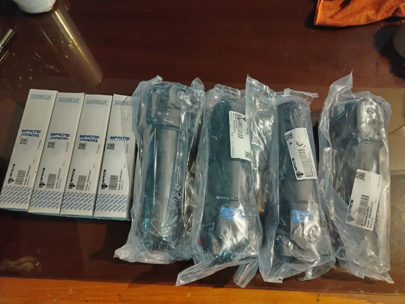 Cuatro elementos filtrantes MP Filtri en sus cajas y cuatro carcasas de filtro embolsadas sobre una mesa